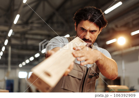 Young carpenter man looking and choosing wood plank at workshop in carpenter wood factory Young carpenter man looking and choosing wood plank at workshop in carpenter wood factory 106392909
