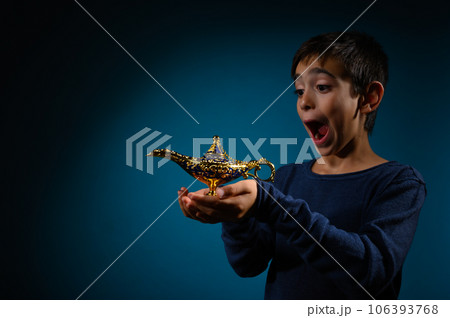 Amazed child with magic Aladin lamp in hand 106393768