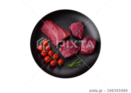 Juicy raw beef with spices, salt and herbs on a dark concrete background Juicy raw beef with spices, salt and herbs on a dark concrete background 106393980
