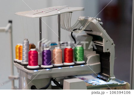 Multi-colored spools of thread are connected to an embroidery machine Multi-colored spools of thread are connected to an embroidery machine 106394106