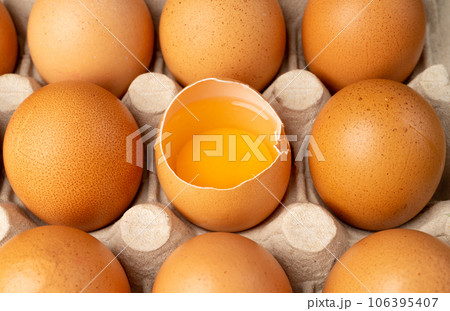 Whole Chicken Eggs and One Broken Closeup, Broken Egg in Carton Pack, Brown Hen Eggs Container Whole Chicken Eggs and One Broken Closeup, Broken Egg in Carton Pack, Brown Hen Eggs Container 106395407