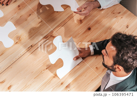 Businessmen working together to build a puzzle as teamwork, partnership and integration concept Businessmen working together to build a puzzle as teamwork, partnership and integration concept 106395471