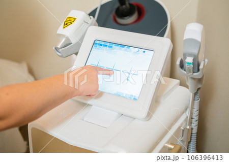 Close up cosmetologist hand tries to adjust settings of laser depilation. 106396413