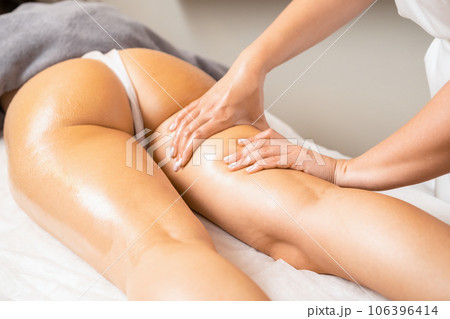 Female masseur performs massage for buttocks with professional moves. Professional cosmetologist does anti-cellulite massage on woman client body Female masseur performs massage for buttocks with professional moves. Professional cosmetologist does anti-cellulite massage on woman client body 106396414