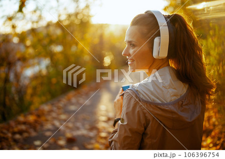 smiling elegant woman in park listening to music smiling elegant woman in park listening to music 106396754
