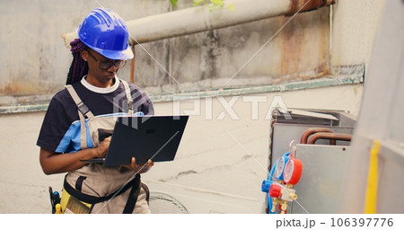 Experienced engineer working on external hvac system, holding laptop. Meticulous wireman optimizing outdoor condenser performance, ensuring it operates at maximum capacity 106397776