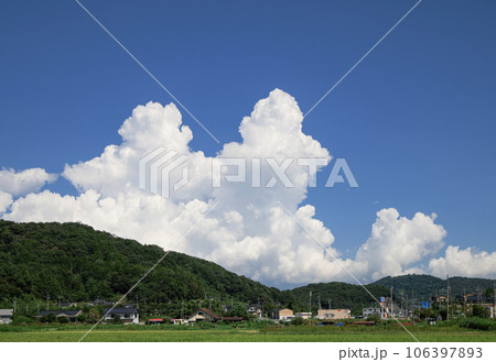 山の向こうから立ち上る入道雲と田園風景の写真素材 [106397893] - PIXTA