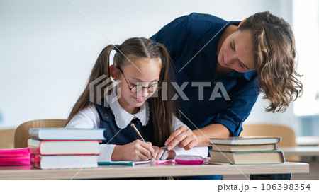 The teacher explains the task to the schoolgirl in the classroom. 106398354