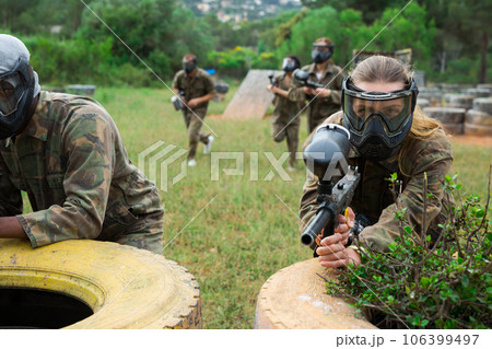 Group of friends paintball players of opposite teams in shootout in forest 106399497