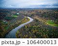 Above aerial shot of green pine forests and yellow foliage groves with beautiful texture of golden treetops. Beautiful fall season scenery in evening. Mountains in autumn colors in golden time 106400013