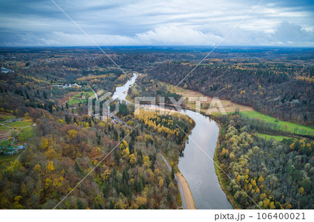 Above aerial shot of green pine forests and yellow foliage groves with beautiful texture of golden treetops. Beautiful fall season scenery in evening. Mountains in autumn colors in golden time 106400021