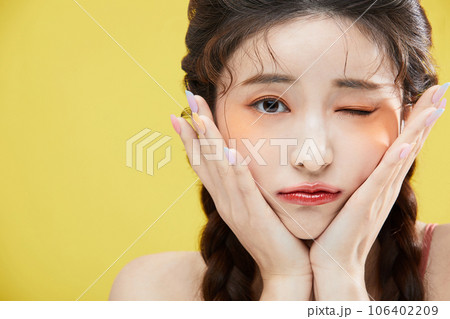beauty concept photo of korean asain beautiful woman resting her chin on her hand and giving a wink 106402209