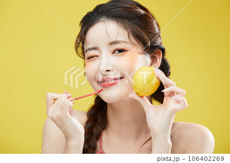 beauty concept photo of korean asain beautiful woman holding a lipgloss and a lemon beauty concept photo of korean asain beautiful woman holding a lipgloss and a lemon 106402269