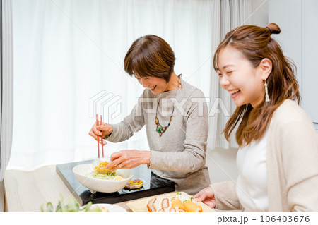 キッチンでサンドイッチを盛り付ける母と娘の2人 キッチンでサンドイッチを盛り付ける母と娘の2人 106403676