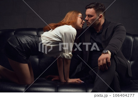 Handsome man and sexy woman sitting on leather couch ready to kiss Handsome man and sexy woman sitting on leather couch ready to kiss 106404277