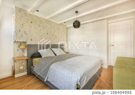 a bedroom with a bed, chair and wallpapered walls in the room behind it is a white door a bedroom with a bed, chair and wallpapered walls in the room behind it is a white door 106404998