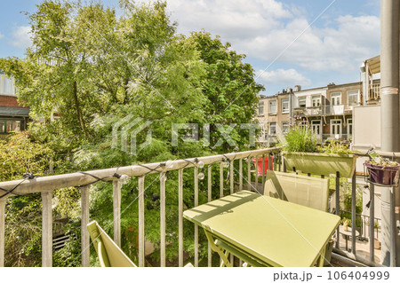 a green table and chairs on a balcony with trees in the back ground, some buildings are visible in the background a green table and chairs on a balcony with trees in the back ground, some buildings are visible in the background 106404999