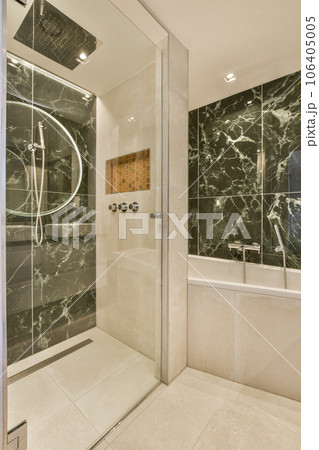 a modern bathroom with marble walls and tile flooring in the shower stall is shown to the right, there is a large mirror 106405005