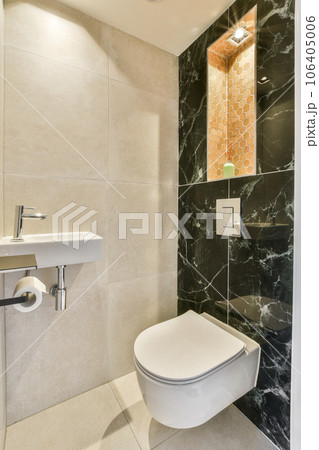 a bathroom with black and white marble on the walls, along with a toilet in the wall is decorated with an orange mosaic tile 106405006