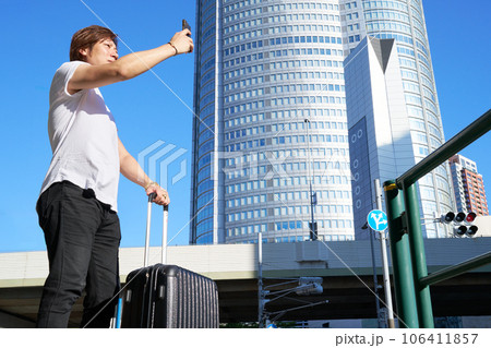 スーツケースを持って路上でスマホを操作する男性 スーツケースを持って路上でスマホを操作する男性 106411857