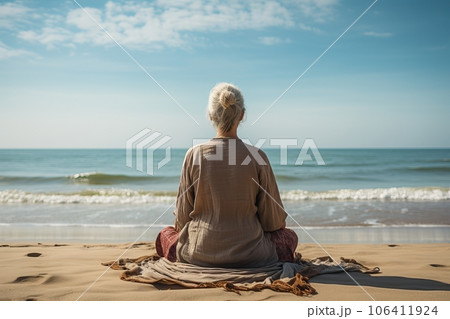 An elderly woman sits on the seashore and meditates. Rest and relaxation. generative AI 106411924