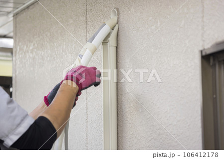 屋外のエアコンの配管を取り付ける男性手元　エアコン取り付け工事 106412178