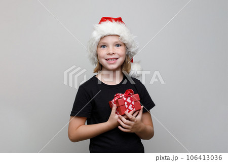 Christmas kid girl in Santa hat holding red gift box on white background, Xmas portrait Christmas kid girl in Santa hat holding red gift box on white background, Xmas portrait 106413036