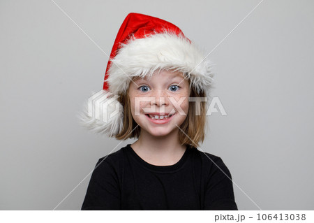 Christmas child girl in Santa hat looking at camera on white background, Xmas portrait Christmas child girl in Santa hat looking at camera on white background, Xmas portrait 106413038