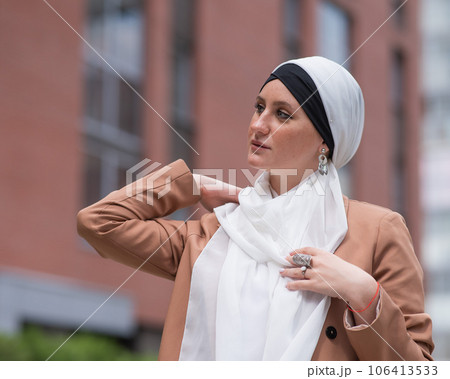 Young woman dressed in hijab and business suit walking outdoors. Young woman dressed in hijab and business suit walking outdoors. 106413533