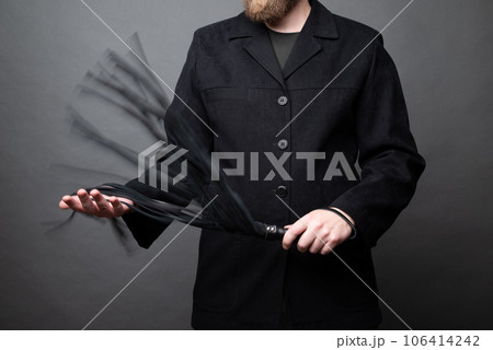 male dominant holds a leather whip Flogger for hard BDSM sex with spanking 106414242