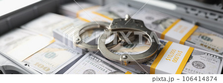 Handcuffs on pile of cash in suitcase 106414874