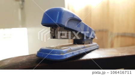 closeup view of an old rustic plastic stapler isolated on brown wooden background 106416711