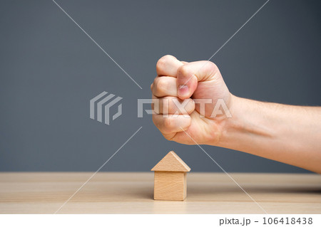 The fist aims at the house. Collectors. Concept of threat to house and real estate and business. The threat of a strike at prices. Aggression on the market. The fist aims at the house. Collectors. Concept of threat to house and real estate and business. The threat of a strike at prices. Aggression on the market. 106418438