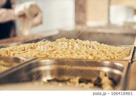 Self-service canteen at the training center. Close-up of boiled pasta on a metal tray. High quality photo Self-service canteen at the training center. Close-up of boiled pasta on a metal tray. High quality photo 106418901