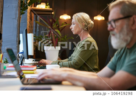 Concentrated senior people, man and woman working on laptop on projects in office. Business atmosphere Concentrated senior people, man and woman working on laptop on projects in office. Business atmosphere 106419298