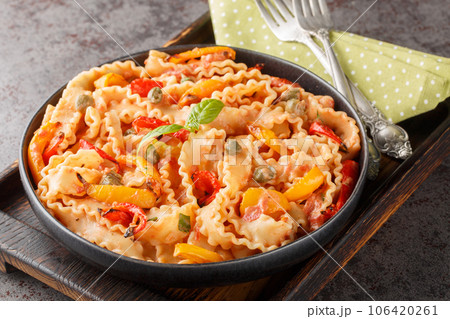 Ribbon-shaped Italian pasta mafaldine cooked with creamy tomato sauce and bell peppers close-up in a bowl. horizontal Ribbon-shaped Italian pasta mafaldine cooked with creamy tomato sauce and bell peppers close-up in a bowl. horizontal 106420261