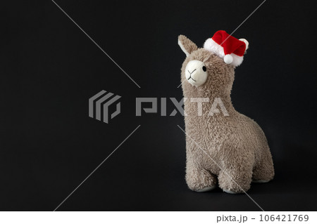 Toy lama in Christmas Santa hat black background. Copyspace. Toy lama in Christmas Santa hat black background. Copyspace. 106421769