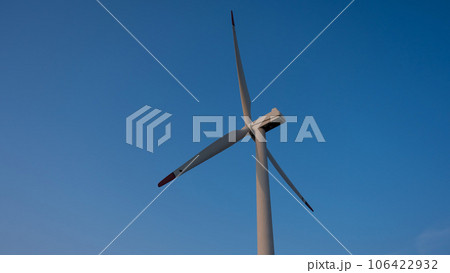 Bottom view of a windmill against a blue sky. Alternative energy source. Bottom view of a windmill against a blue sky. Alternative energy source. 106422932