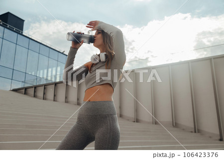 Fitness woman drinking water outdoors 106423376