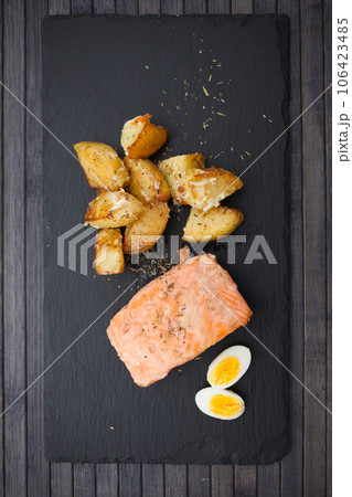 Steamed salmon fillet with potato wedges and quail egg Steamed salmon fillet with potato wedges and quail egg 106423485