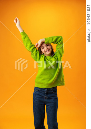 Portrait of a joyful happy teenage girl celebrating success on yellow background 106424885