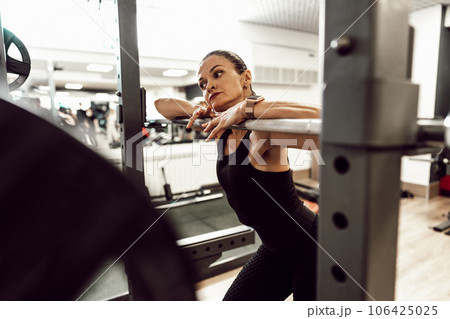 Fit woman doing squats with barbell in a gym Fit woman doing squats with barbell in a gym 106425025