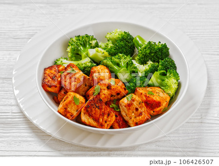 fried salmon bites with steamed broccoli florets 106426507