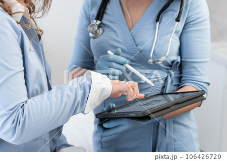 Diagnosis and advice: A woman at the doctor's reception who expertly examines the data on the tablet, providing the patient with a diagnosis and recommendations. Tablet examination: A doctor shows a Diagnosis and advice: A woman at the doctor's reception who expertly examines the data on the tablet, providing the patient with a diagnosis and recommendations. Tablet examination: A doctor shows a 106426729