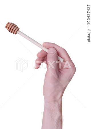 A man holds a wooden spoon for honey in his hand. Isolated on a white background. A man holds a wooden spoon for honey in his hand. Isolated on a white background. 106427427