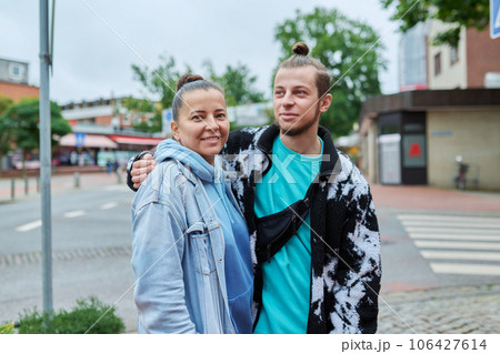 Portrait of 18, 19 year old son embracing with his mother, outdoor 106427614