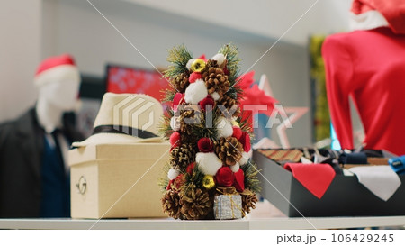 Close up shot of festive Christmas decorations in clothing store during winter holiday season. Display of xmas ornaments, garlands and formal attire clothes in fashion boutique Close up shot of festive Christmas decorations in clothing store during winter holiday season. Display of xmas ornaments, garlands and formal attire clothes in fashion boutique 106429245