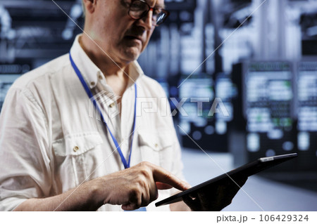 Senior supervisor inspects operational server rigs in computer network security data center, ensuring errorless performance. Trained expert monitoring energy consumption across hardware parts Senior supervisor inspects operational server rigs in computer network security data center, ensuring errorless performance. Trained expert monitoring energy consumption across hardware parts 106429324