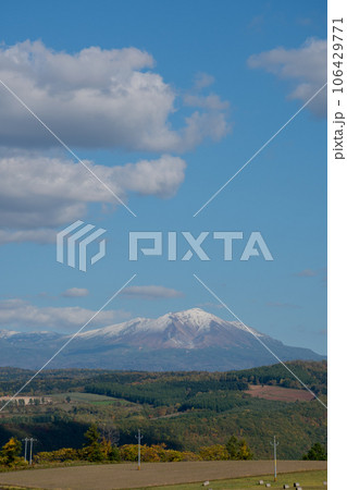 秋の畑作地帯と冠雪の山並み 106429771