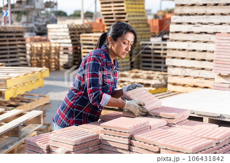 Woman places paving slabs on a pallet in building materials warehouse Woman places paving slabs on a pallet in building materials warehouse 106431842